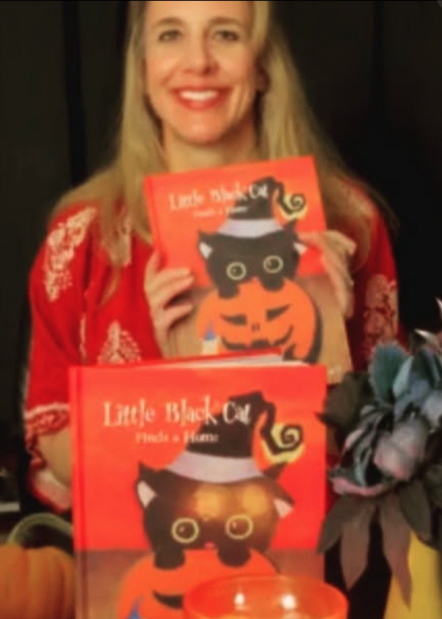 A. J. Kemner smiling and holding two copies of Little Black Cat Finds a Home.